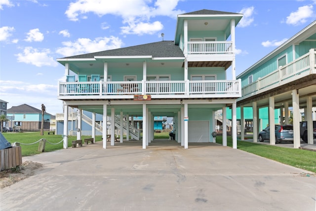 rear view of house with a lawn, a carport, a balcony, and a garage