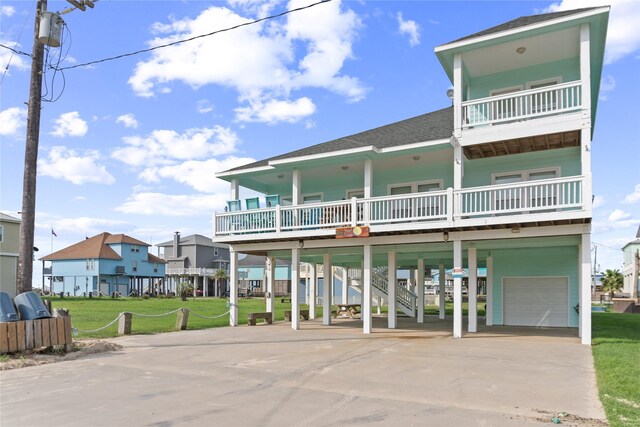 view of front of home with a front yard, a porch, a balcony, a carport, and a garage