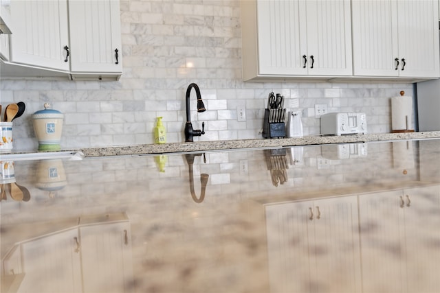 kitchen featuring light stone counters, white cabinetry, and extractor fan