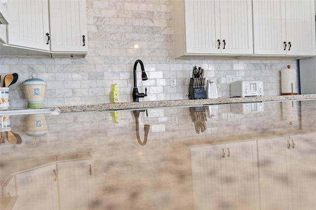 833 S Oneal Rd, Crystal Beach, TX 77650 - kitchen with decorative backsplash, light stone countertops, white cabinetry, and range hood