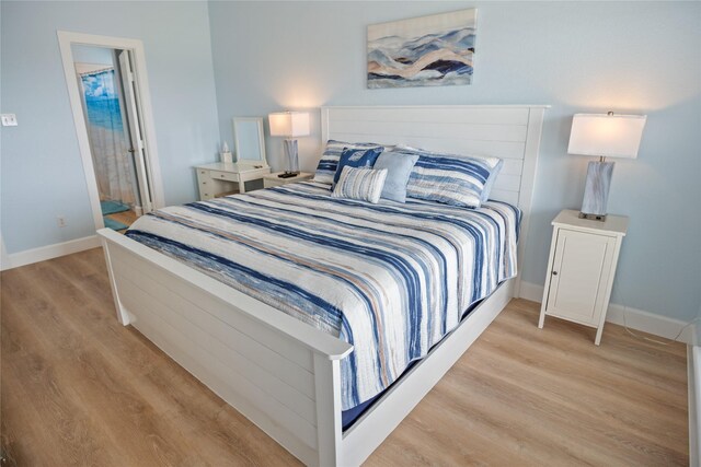 bedroom with ensuite bath and light hardwood / wood-style floors