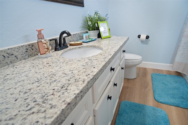 bathroom with toilet, hardwood / wood-style flooring, and vanity