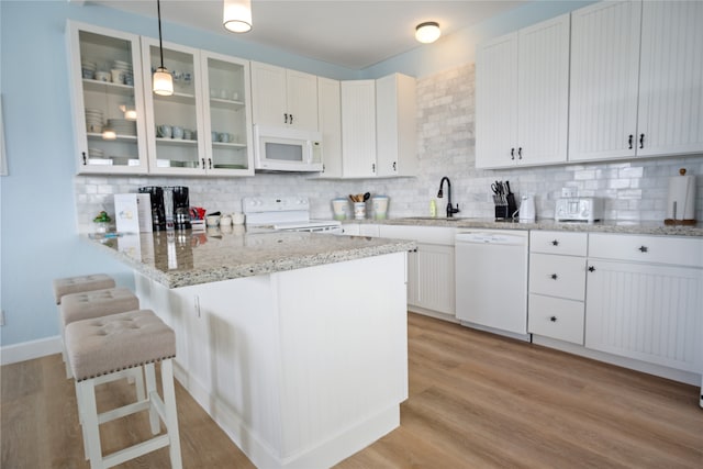 kitchen with light wood-type flooring, white appliances, kitchen peninsula, and tasteful backsplash