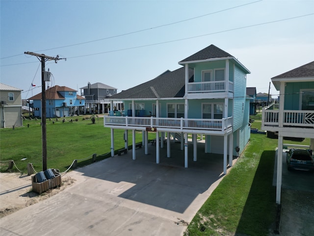 rear view of property featuring a balcony, a lawn, and a carport