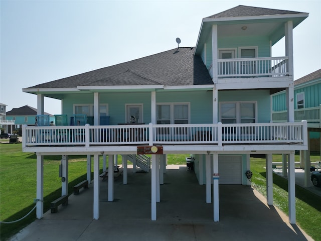 rear view of house with a yard, a garage, a carport, and a balcony