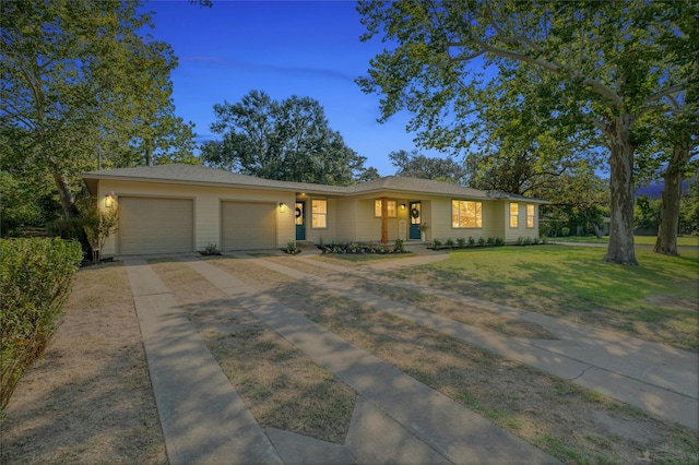 ranch-style house with covered porch, a yard, and a garage