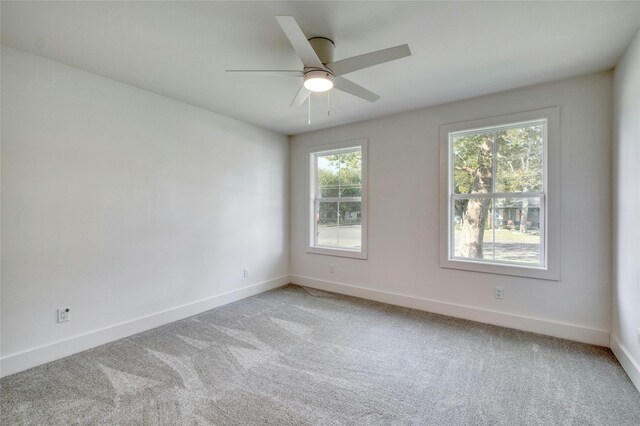 spare room with ceiling fan, baseboards, and light colored carpet