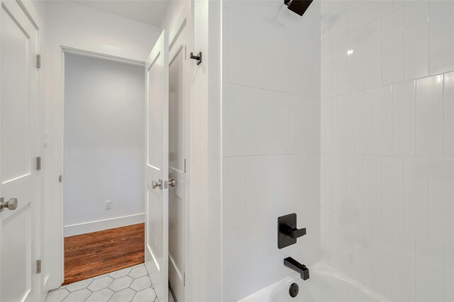 bathroom featuring shower / bathing tub combination, baseboards, and wood finished floors