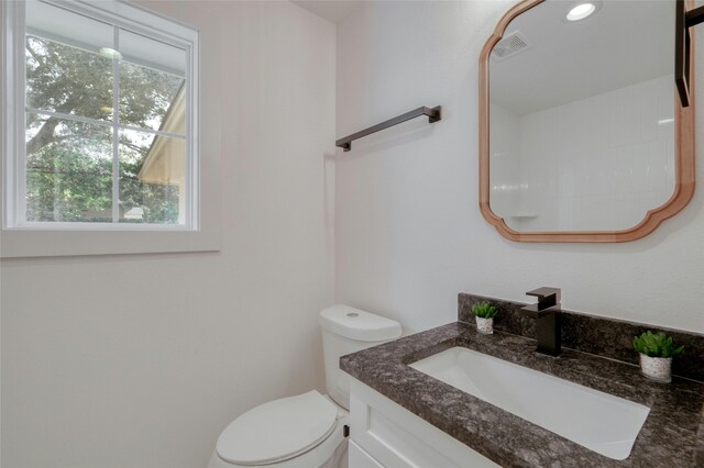 bathroom featuring toilet, vanity, and visible vents