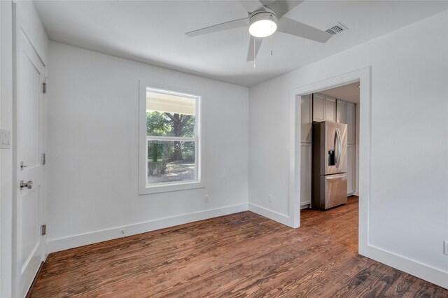 empty room with a ceiling fan, visible vents, baseboards, and wood finished floors