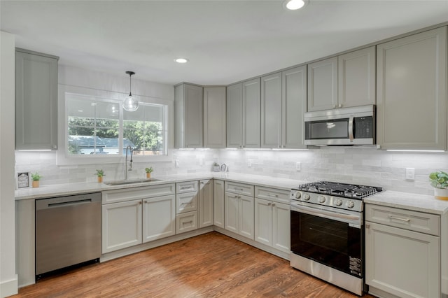 kitchen featuring light stone counters, recessed lighting, stainless steel appliances, a sink, and light wood-type flooring