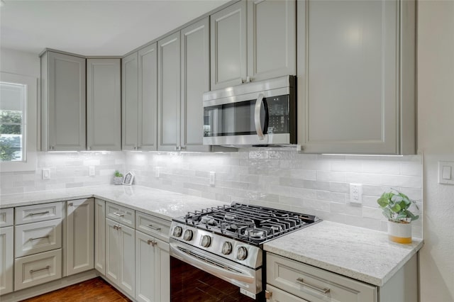 kitchen featuring light stone countertops, stainless steel appliances, decorative backsplash, and wood finished floors