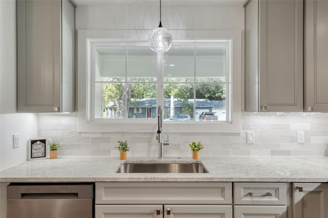 kitchen featuring light stone counters, pendant lighting, backsplash, a sink, and dishwasher