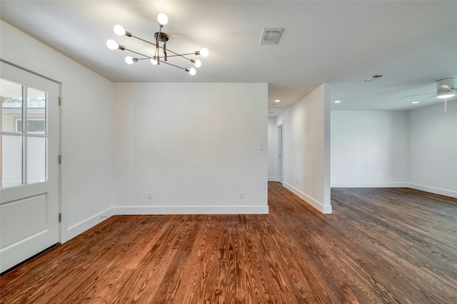 spare room with baseboards, visible vents, wood finished floors, and ceiling fan with notable chandelier