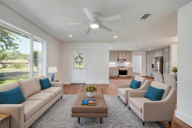 living room with recessed lighting, visible vents, light wood-style floors, a ceiling fan, and baseboards