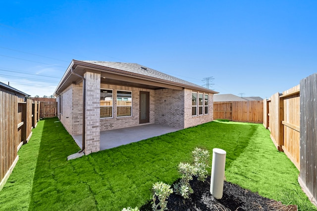 rear view of property featuring a patio area, brick siding, a yard, and a fenced backyard