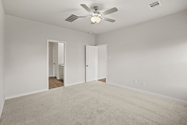 unfurnished bedroom featuring light colored carpet, ensuite bathroom, and ceiling fan