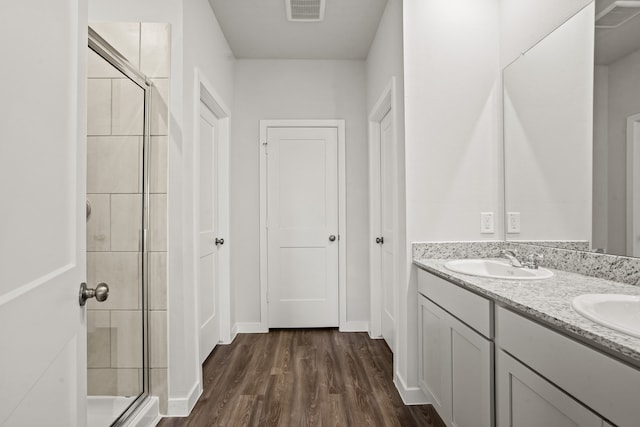 bathroom with hardwood / wood-style floors, a shower with shower door, and vanity