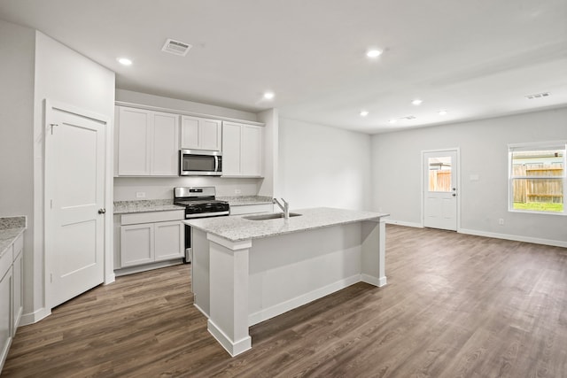 kitchen with sink, white cabinets, light stone counters, a center island with sink, and stainless steel appliances