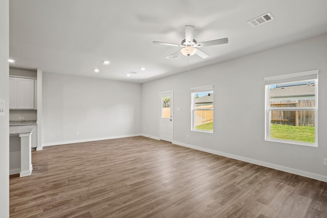 unfurnished living room featuring dark wood-type flooring and ceiling fan