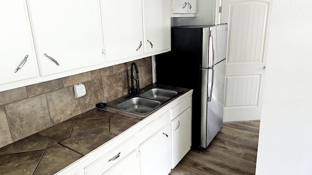 kitchen featuring sink, white cabinetry, decorative backsplash, and stainless steel fridge