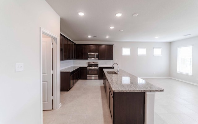 kitchen featuring sink, dark brown cabinets, stainless steel appliances, plenty of natural light, and an island with sink