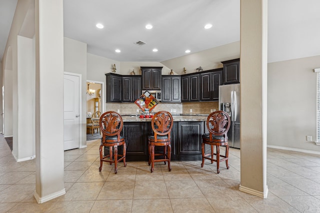 kitchen with a kitchen breakfast bar, stainless steel appliances, a center island with sink, and light tile patterned floors