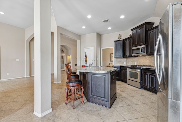 kitchen featuring light tile patterned floors, an island with sink, and stainless steel appliances