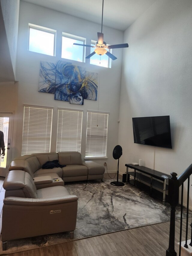 living room with hardwood / wood-style flooring, ceiling fan, and a high ceiling