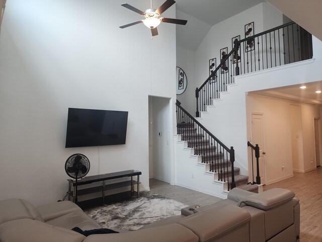 living room with ceiling fan, light wood-type flooring, and high vaulted ceiling