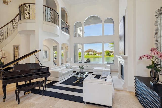 tiled living room featuring a towering ceiling and a water view