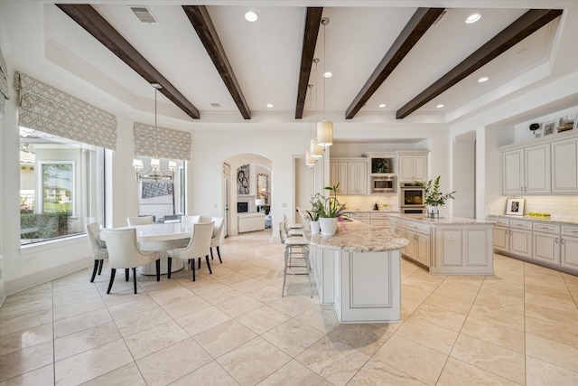 kitchen with a center island, hanging light fixtures, decorative backsplash, and light stone counters