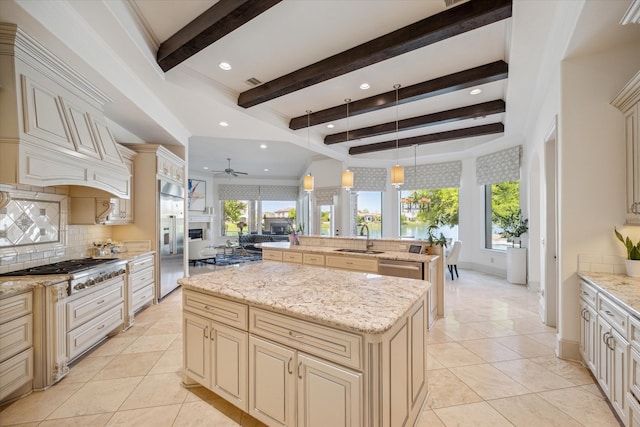 kitchen with ceiling fan, backsplash, a kitchen island, cream cabinetry, and beamed ceiling