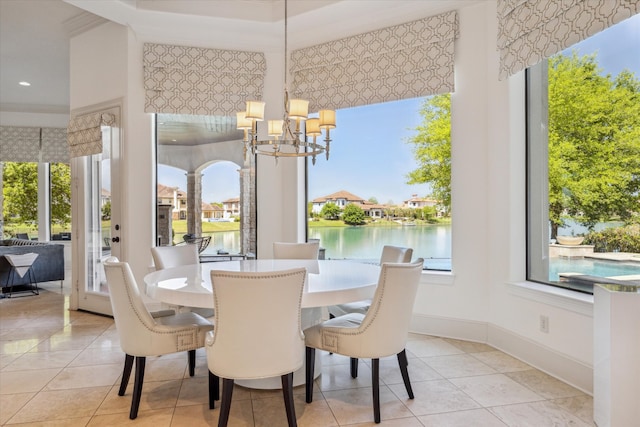 dining room with light tile patterned floors, a notable chandelier, and a water view