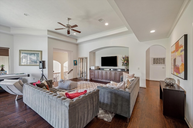 living room with ceiling fan, a raised ceiling, ornamental molding, and dark hardwood / wood-style floors