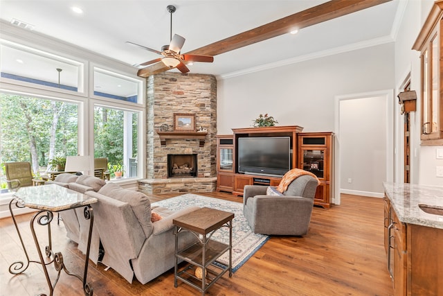 living room featuring a stone fireplace, ceiling fan, crown molding, and light wood-type flooring