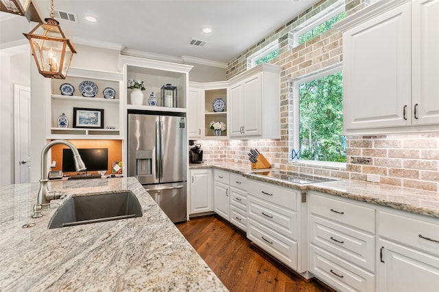 kitchen with white cabinets, sink, hanging light fixtures, light stone counters, and stainless steel fridge with ice dispenser