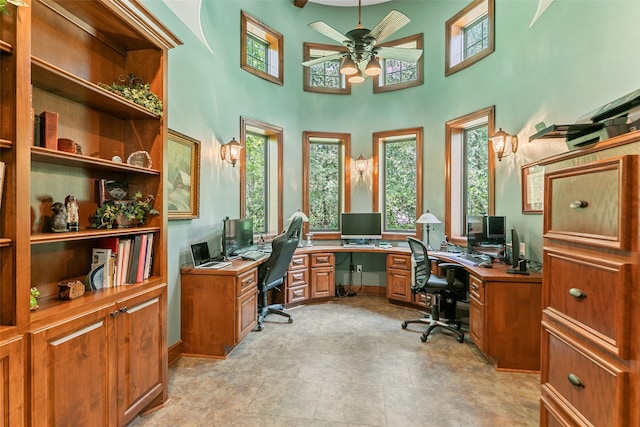 office with a high ceiling, ceiling fan, and a healthy amount of sunlight