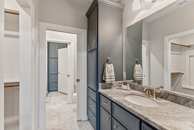 bathroom with toilet, vanity, and tile patterned floors