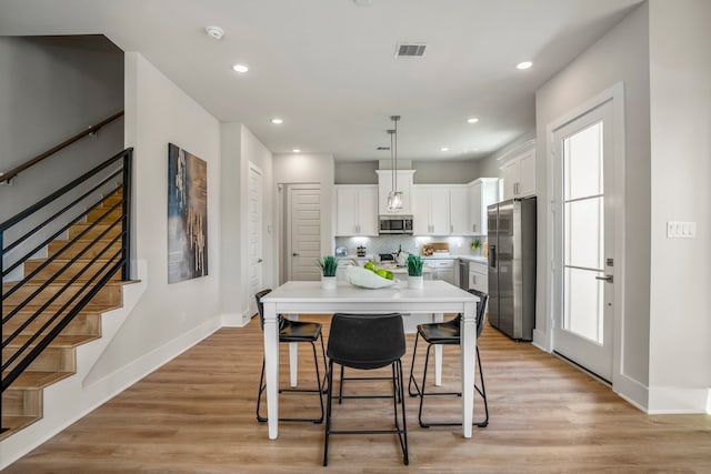 kitchen featuring white cabinets, decorative light fixtures, a kitchen island, and stainless steel appliances