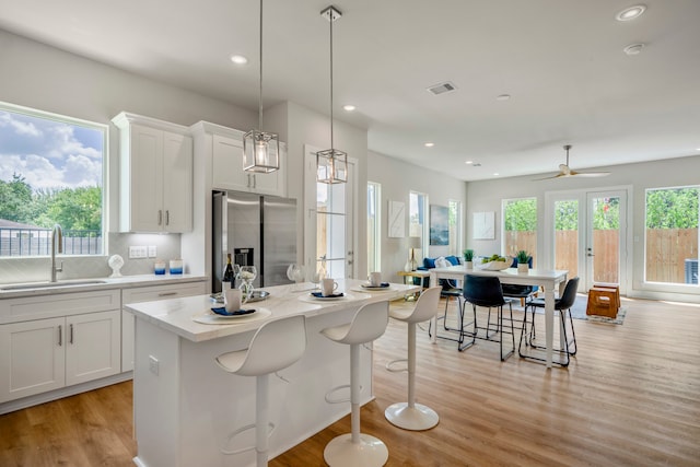 kitchen with white cabinets, stainless steel refrigerator with ice dispenser, a wealth of natural light, and sink