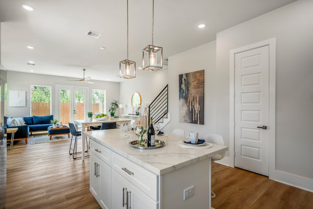 kitchen with white cabinetry, a center island, ceiling fan, pendant lighting, and light wood-type flooring