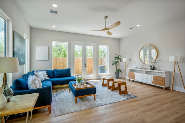 living room with ceiling fan, light hardwood / wood-style floors, a wealth of natural light, and french doors