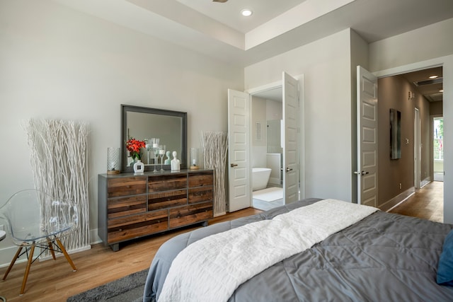 bedroom featuring hardwood / wood-style flooring and ensuite bathroom