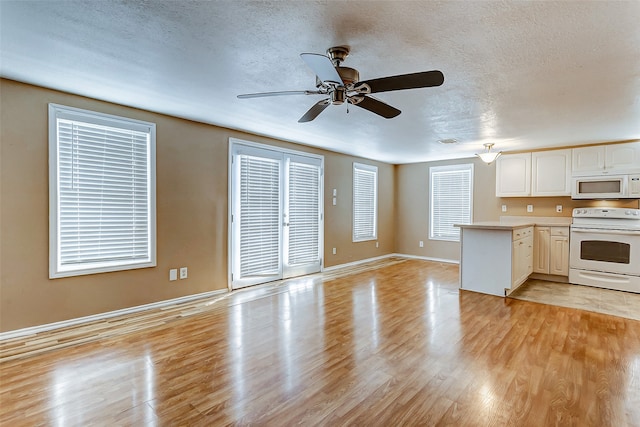 kitchen featuring light wood-type flooring, a textured ceiling, kitchen peninsula, white appliances, and ceiling fan