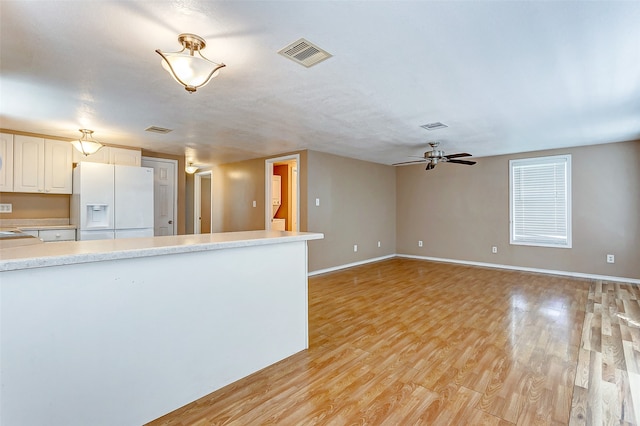 kitchen with ceiling fan, white cabinets, light hardwood / wood-style flooring, and white refrigerator with ice dispenser