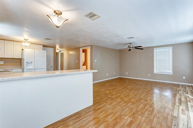 kitchen with visible vents, ceiling fan, light countertops, white refrigerator with ice dispenser, and light wood-style flooring