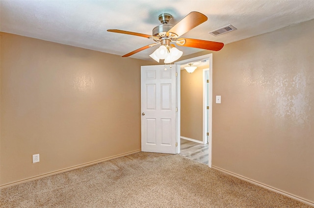 unfurnished room featuring baseboards, visible vents, light colored carpet, and a ceiling fan
