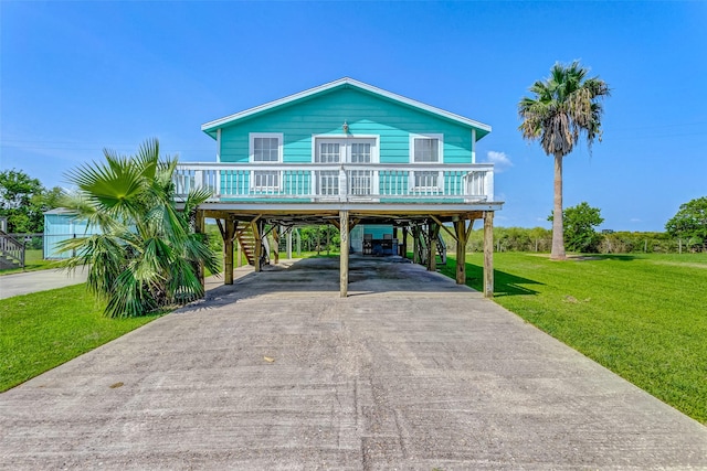 raised beach house featuring aphalt driveway, covered porch, stairway, a carport, and a front yard