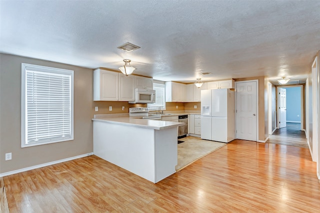 kitchen with light hardwood / wood-style flooring, white cabinetry, kitchen peninsula, white appliances, and ceiling fan